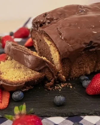 Fertiger Becherkuchen mit Joghurt, übergossen mit Schokolade und zwei Stücke abgeschnitten. Diese liegen daneben.