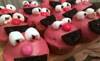 Auf einem Holzbrett stehen ganz viele Muffins, die wie Elmo aussehen.