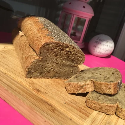 Ein frisch gebackenes Chiabrot. Es liegt aufgeschnitten auf einem Holzbrett.