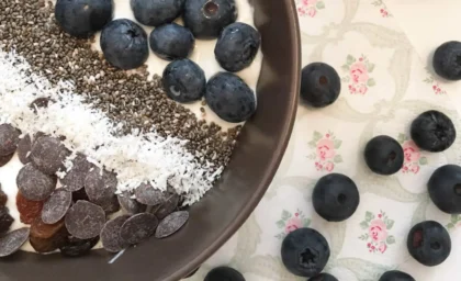 In einer Schüssel ist griechischer Joghurt getopped mit Blaubeeren, Chiasamen und Schokodrops.