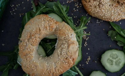 Nahaufnahme von einem veganem Bagel mit Sesam, belegt mit Ruccola und Gurke.