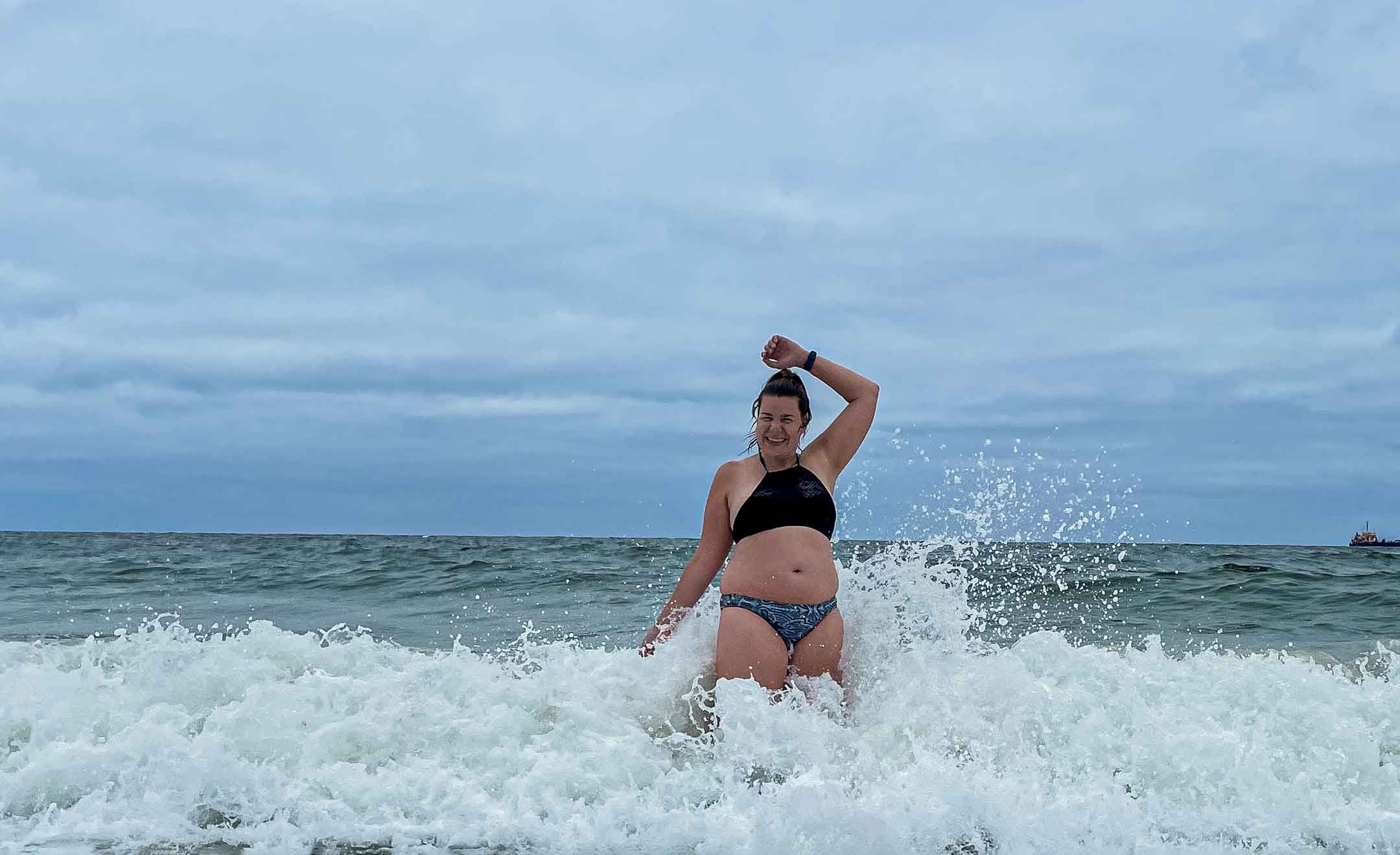 Annkathrin steht im Meer. Um sie herum brechen die Wellen ein.