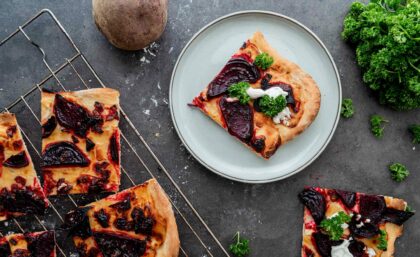 Stücke vom Flammkuchen mit Rote Beete und Zwiebeln auf einem Teller.