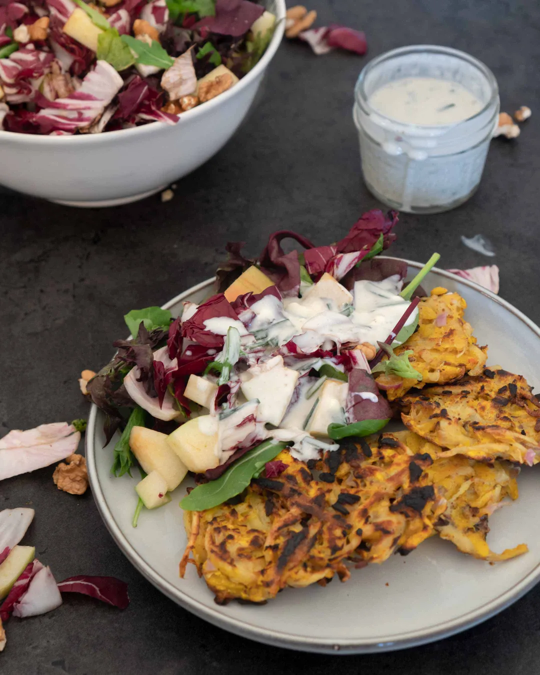 Auf einem Teller liegen vegane Kürbis-Rösti, daneben Radicchio-Salat