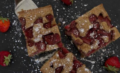 Drei Stücke Erdbeerblechkuchen mit Puderzucker bestreut