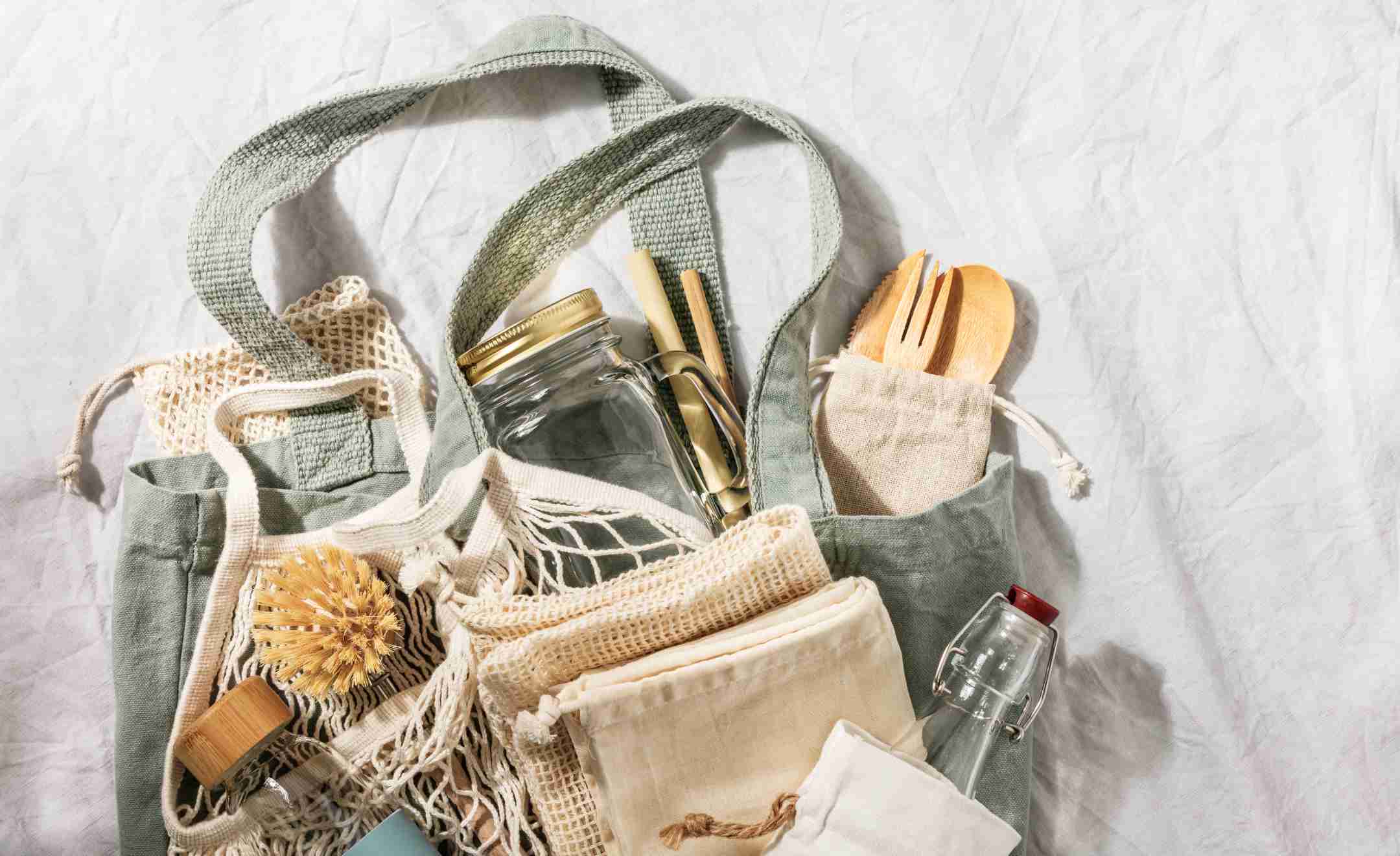 Flatlay von verschiedenen Zero Waste Produkten mit Bambus-Besteck, Gläsern, Bürsten, Jutebeutel und Gemüsenetze