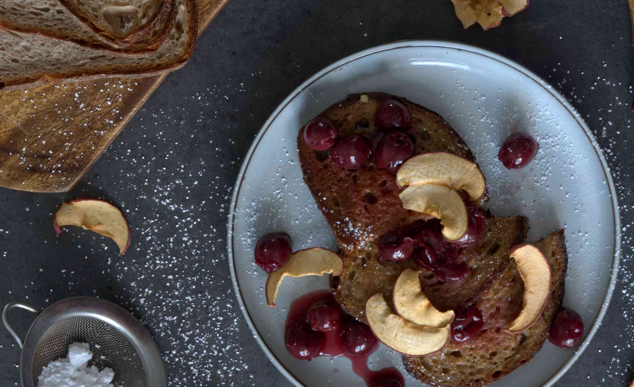 Nahaufnahme: Veganes French-Toast auf einem Teller, getoppt mit Sauerkirschen und Äpfelscheiben.