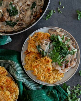 von oben fotografiert: Kartoffelrösties mit Champignon-Rahm-Sauce auf einem Teller drapiert.