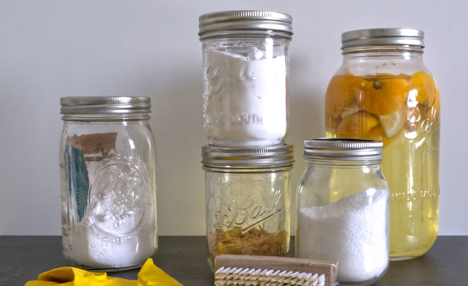 Die fünf Hausmittel Natron, Soda, Essig, Zitronensäure und Kernseife in Mason Jars.