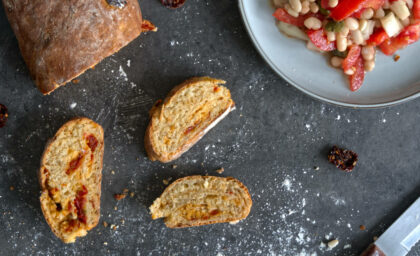 Aufgeschnittenes selbstgebackenes Ciabatta von oben fotografiert. Daneben ein Bohnensalat.